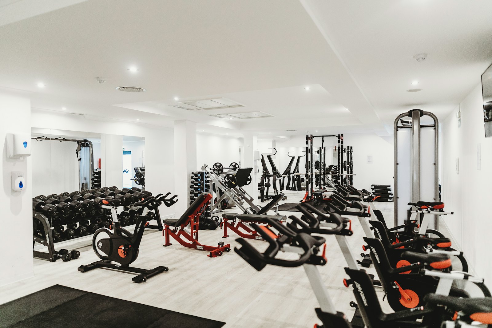 A bright training room with exercise bikes, benches and a dumbbell rack